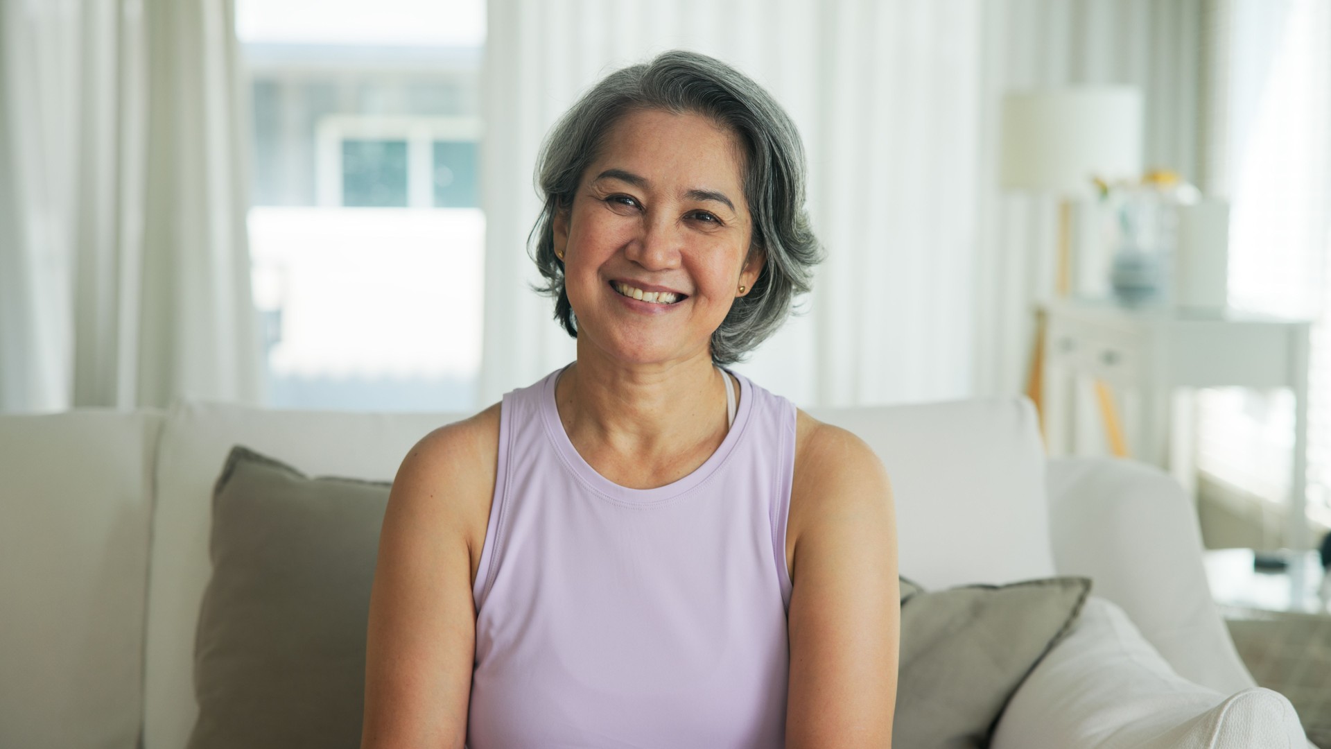 Asia adult active aged people middle age grey hair mom old female joy smile front view look at camera happy face mental health care sit relax at home sofa elder aging life asian single mum parent day.